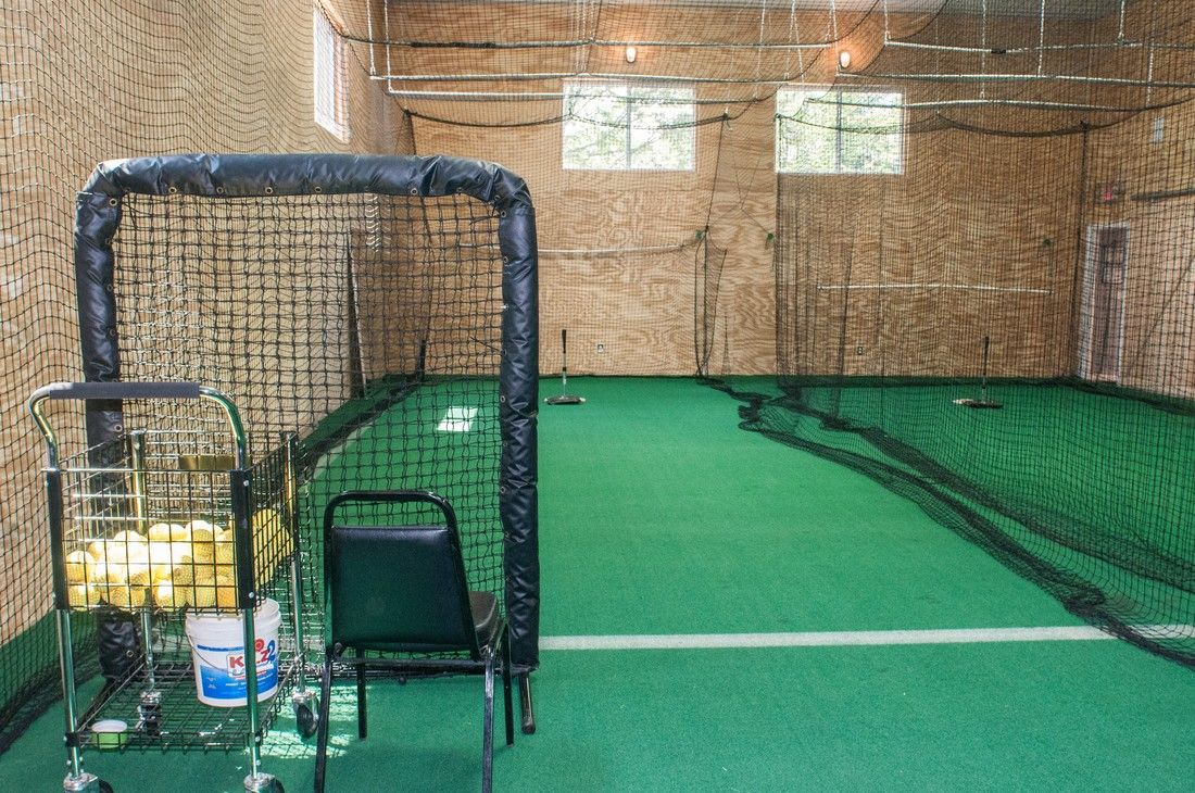 Indoor batting cage with a ball cart and pitching screen