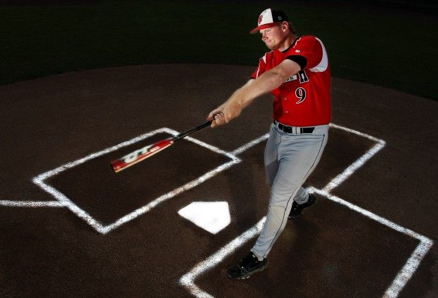 Hitter swinging over home plate under the lights
