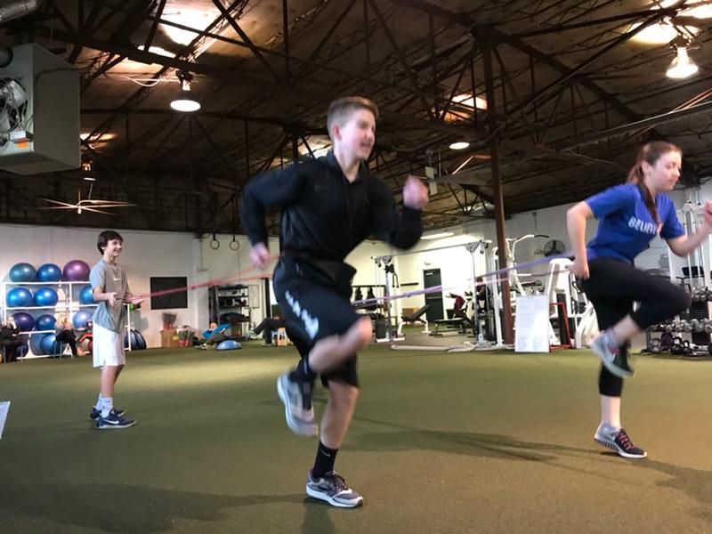 Young athletes sprinting through a resistance drill on indoor turf
